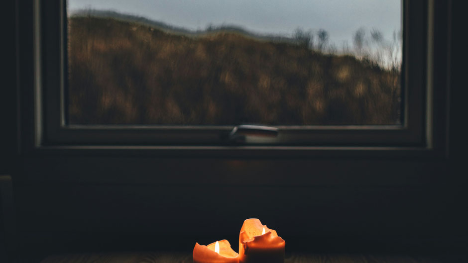 Brennende Kerze vor Fenster. Bild von Thomas Grams auf Unsplash.