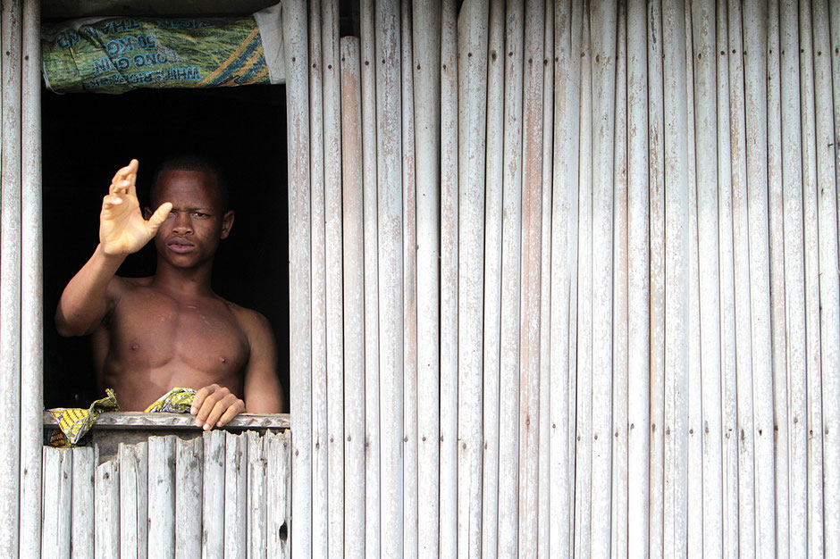 African man waving from the window of a bamboo hut on stilts. Lakeside town. Ganvie.