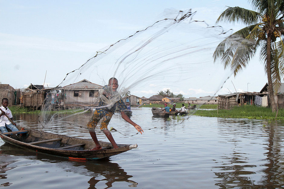 African children fishing with a net on a canoe. Lake Nokoue. Ganvie.