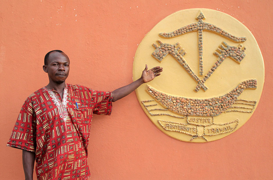 African man shows a mosaic of ink and a boat. The Door of No Return. Ouidah.