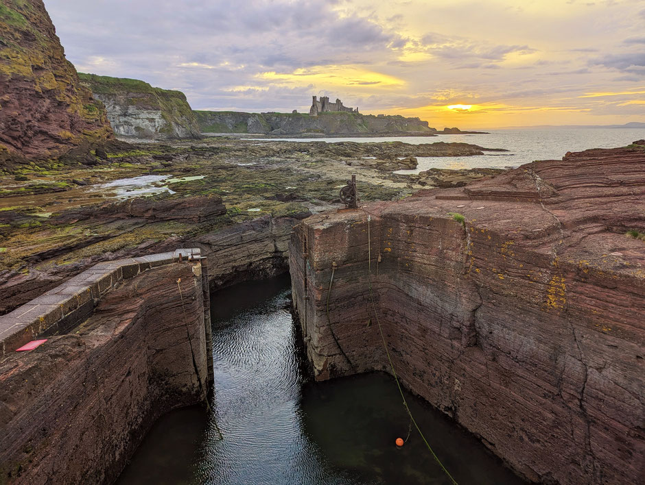 The old harbour of Seacliff with view of Tantallon Castle at sunset.