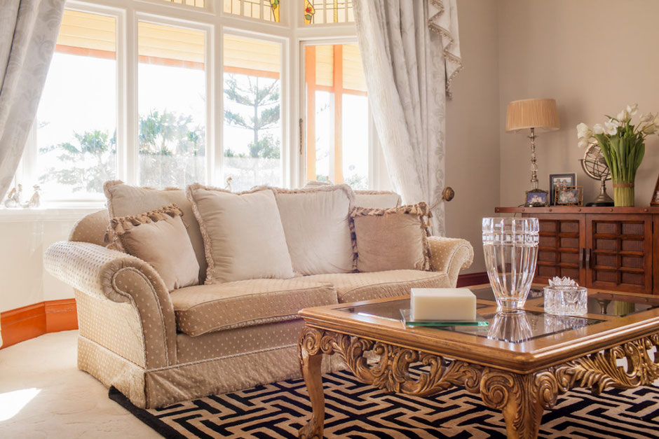 Classic interior design in Newcastle — elegant lounge with carved timber table, textured fabrics, and natural light