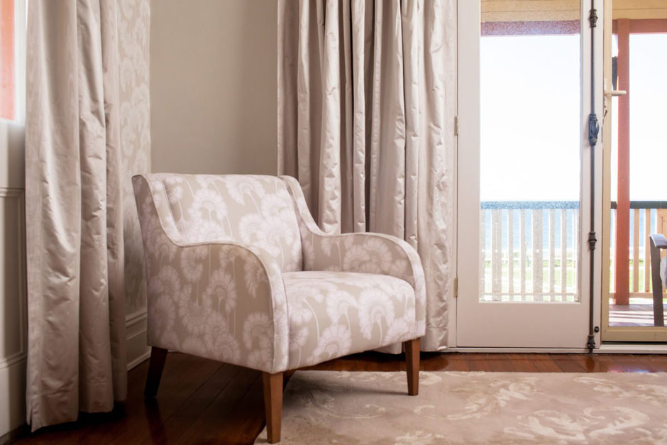Soft grey curtains with matching upholstered armchair in coastal Newcastle home interior