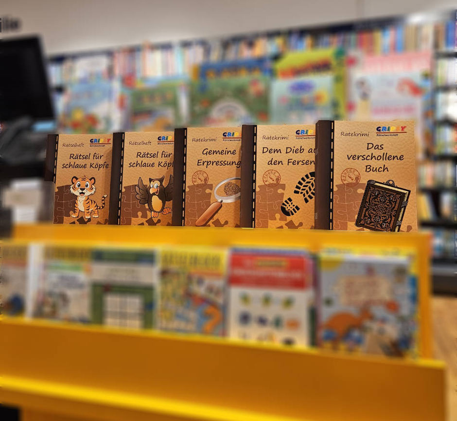 Die drei Ratekrimis "Gemeine Erpressung" und "Dem Dieb auf den Fersen" und "Das verschollene Buch", sowie zwei Rätselhefte im Regal der Buchhandlung Thalia in Amstetten.