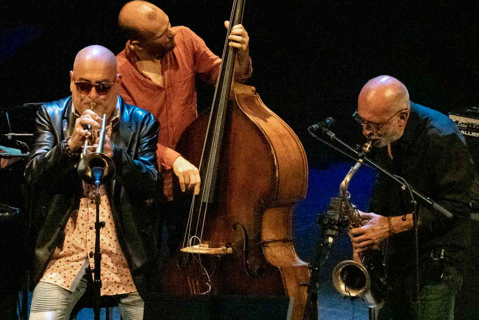 trois musiciens de jazz sur scène, un trompetiste, un saxophoniste et un contrebassiste