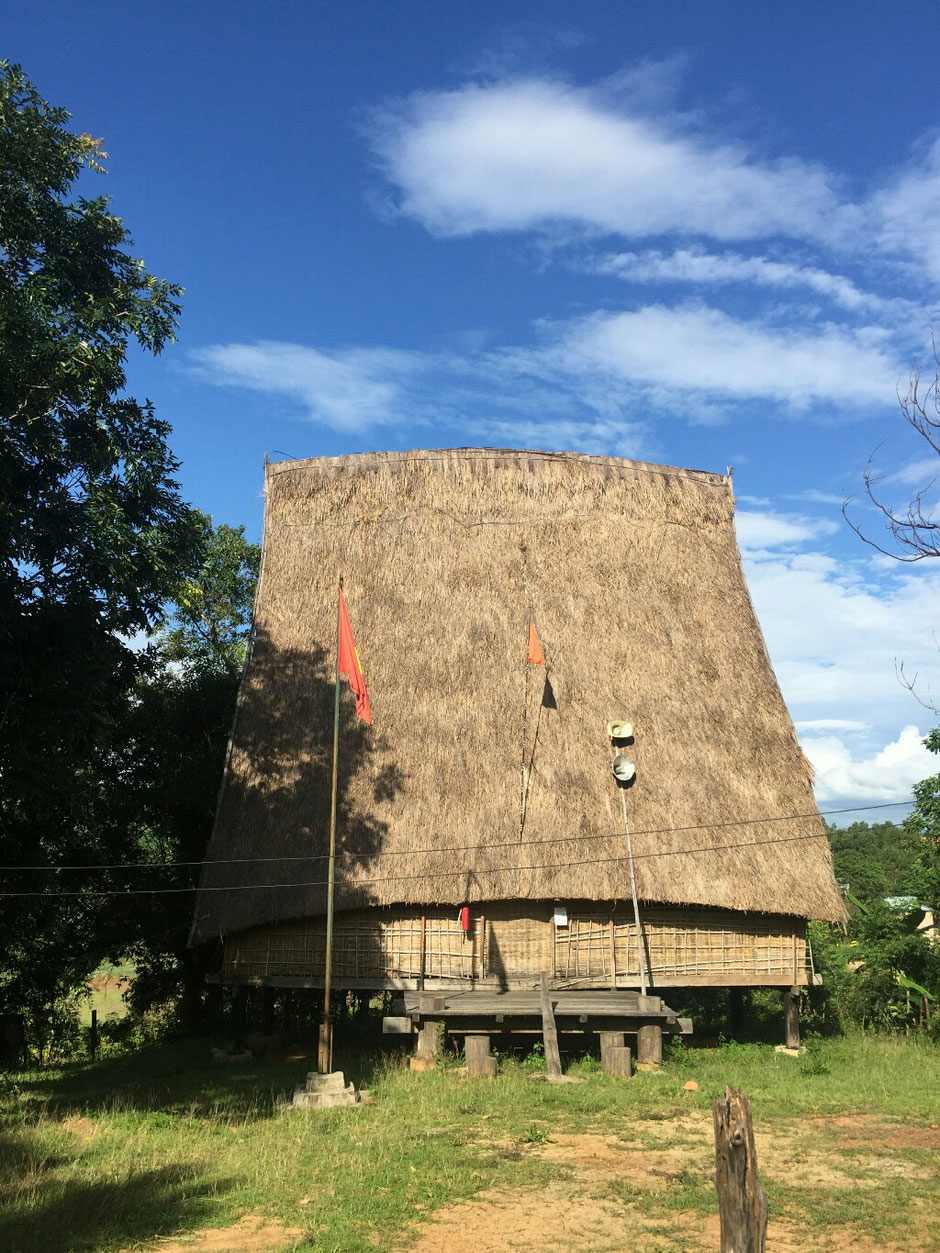 Erkundungstour - zentrales Hochland  - Vietnam – Erkundungstour – Ly und Heiko – Viethouse – Nha Rong - Dorfgemeinschaft – Haus – Gebäude – Dorf – Lautsprecher – Kabel – Strohdach – blauer Himmel – grüne Bäume