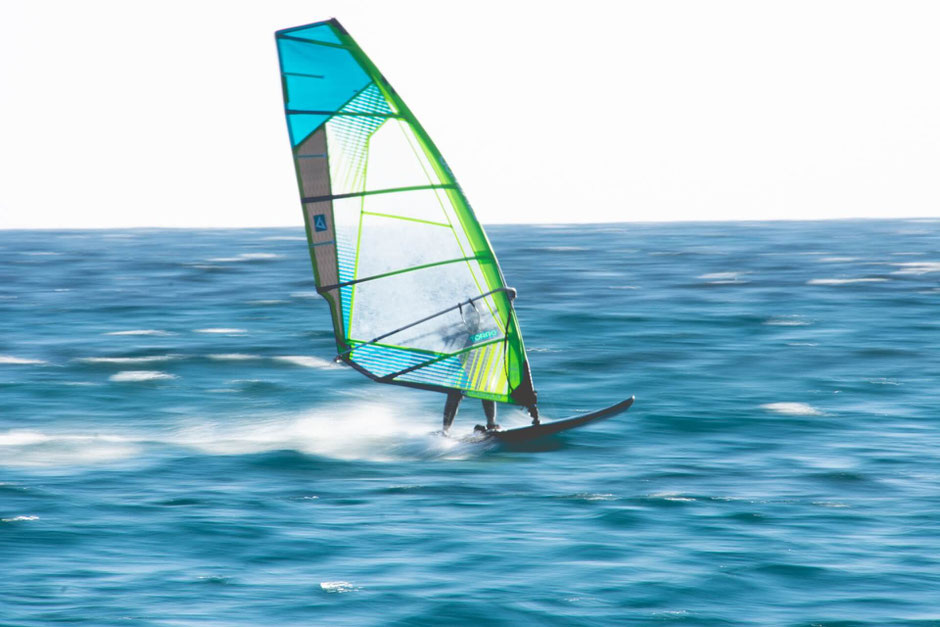 Das Bild zeigt einen Windsurfer, der Artikel beschäftigt sich mit Rippenprellung beim Windsurfen vermeiden
