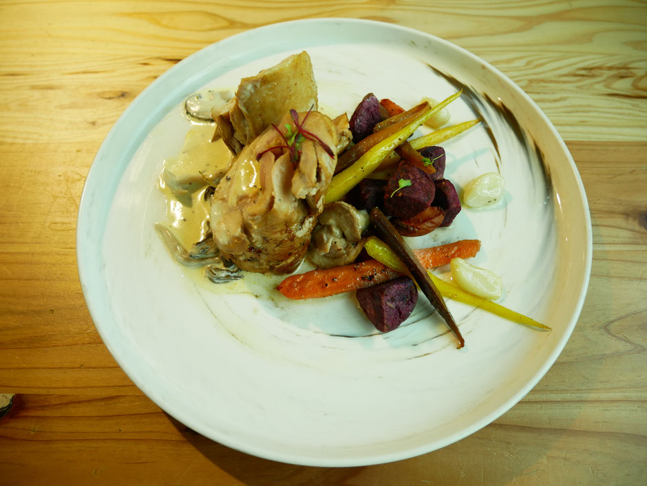 Pan-Seared Lacto Chicken Roulade with a side of sweet potatoes and carrots served on a white plate on wooden table from Mahota Pantry