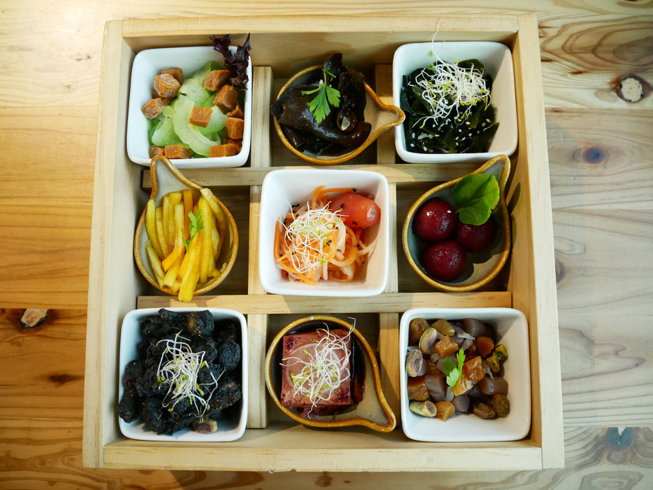 9 different vegetarian dishes in served in a bento box that has been compartmentalised