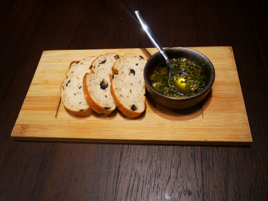 Three slices of gluten free olive bread with a pesto sauce