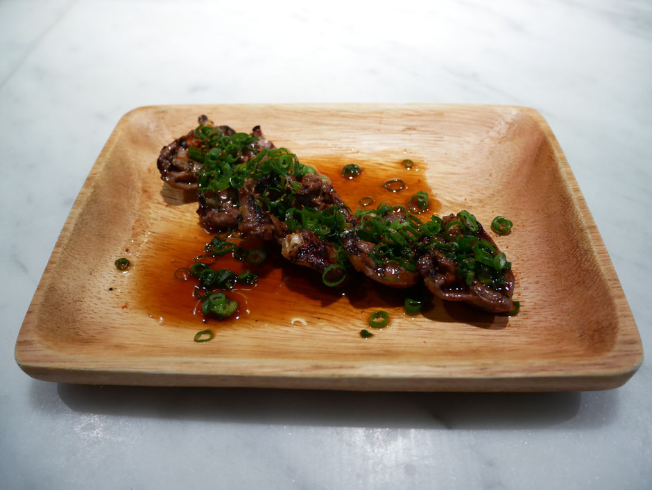 6 chicken hearts served with paprika and sliced spring onion with soy sauce served on a small wooden plate at bincho yakitori singapore