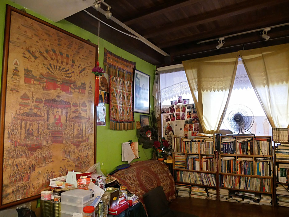 A small breathing decorated with buddhist motif, some books, a fan and a supportive cushion