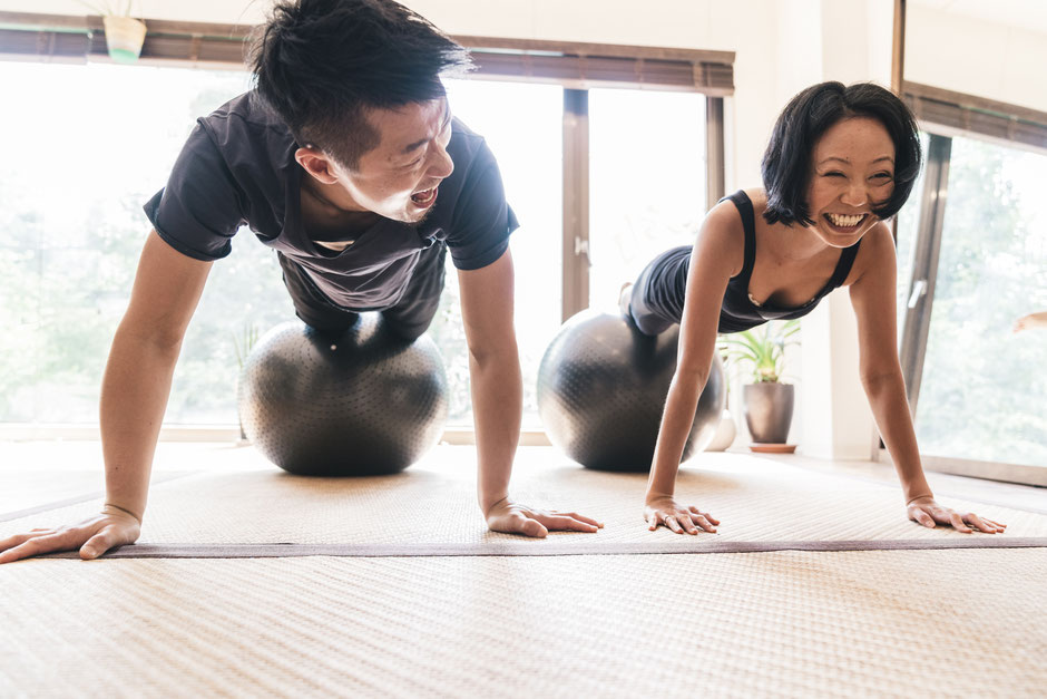 a male personal trainer doing a core exercise with a swiss ball with his client