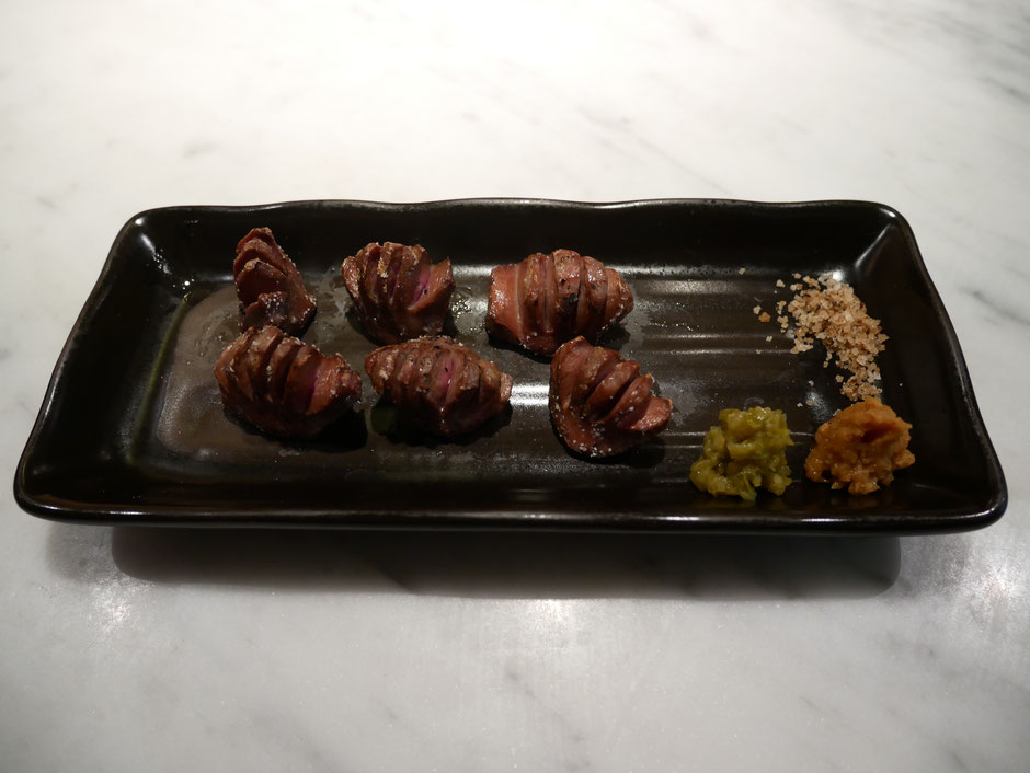 chicken gizzard served with uzu pepper, mountain wasabi and mushroom salt served on a black porcelain plate at bincho yakitori singapore
