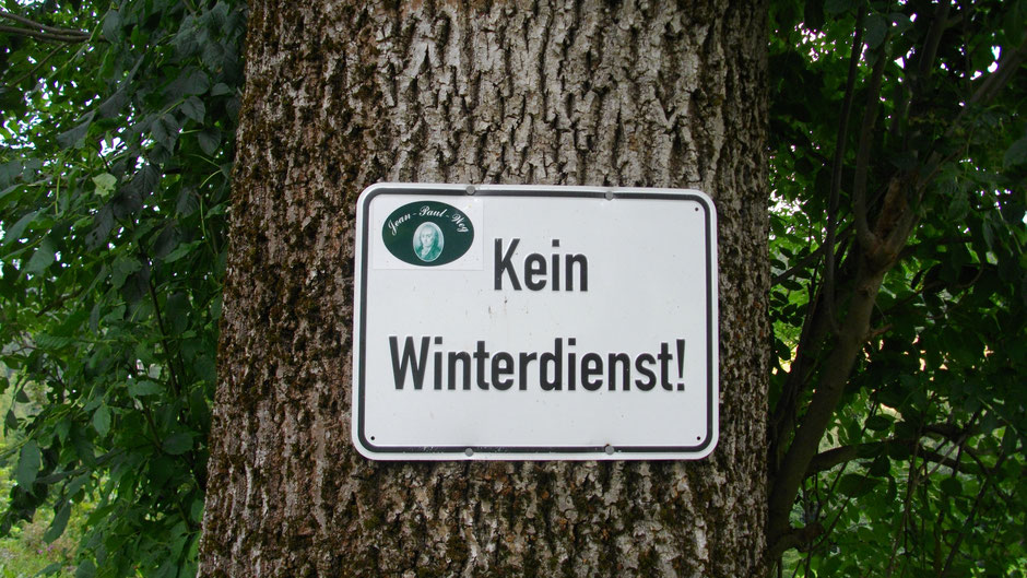 Jean-Paul-Weg Wegmarkierung auf einem Baumstamm mit dem Schild "Kein Winterdienst"