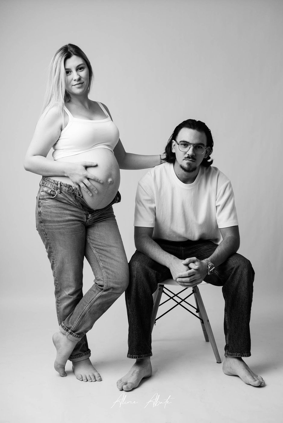 Séance photo grossesse en couple en studio, look moderne jean et débardeur blanc