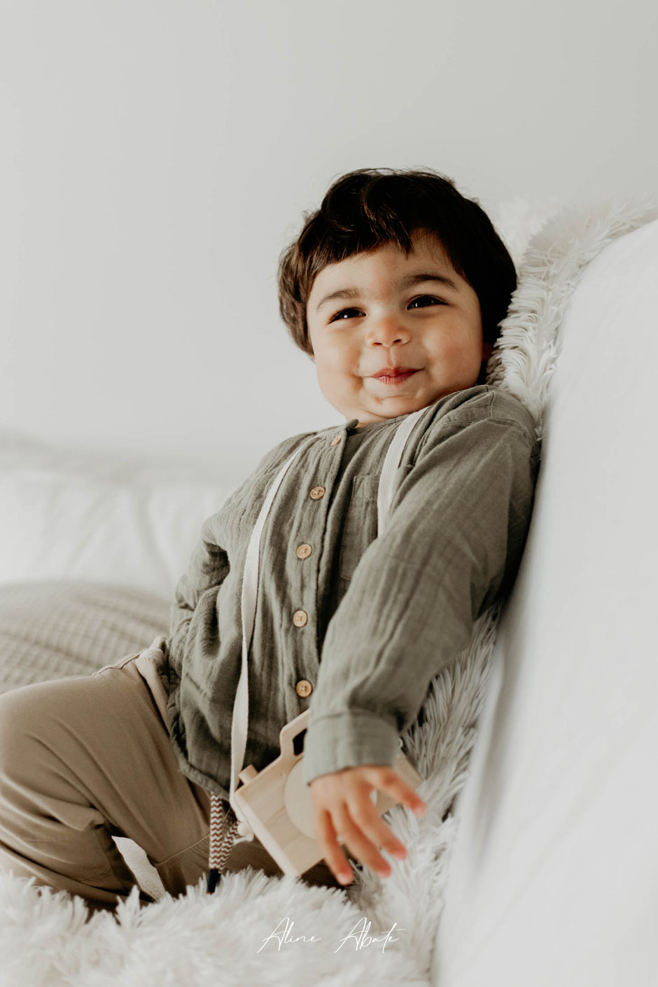 Photographe bébé Maubeuge : Maho assis sur un lit avec une mimique trop craquante