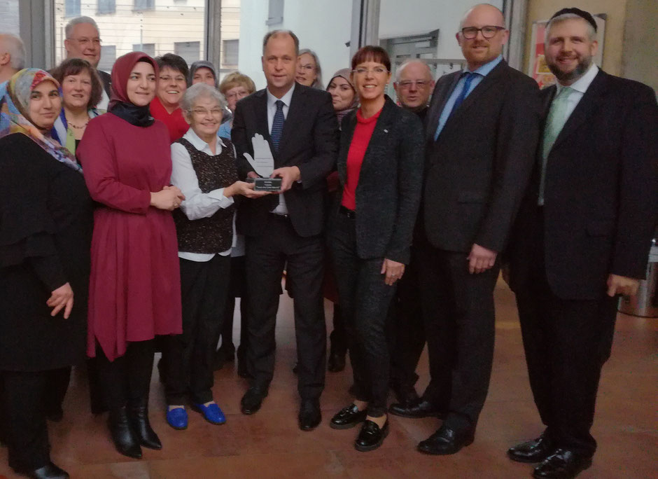 Minister Joachim Stamp übergibt die "Hand" an die Preisträgerinnen. Daneben v.l. Angelika Wagner vom DGB, Stadtdechant Roland Winkelmann, Oberbürgermeister Sören Link und Rabbiner David Geballe