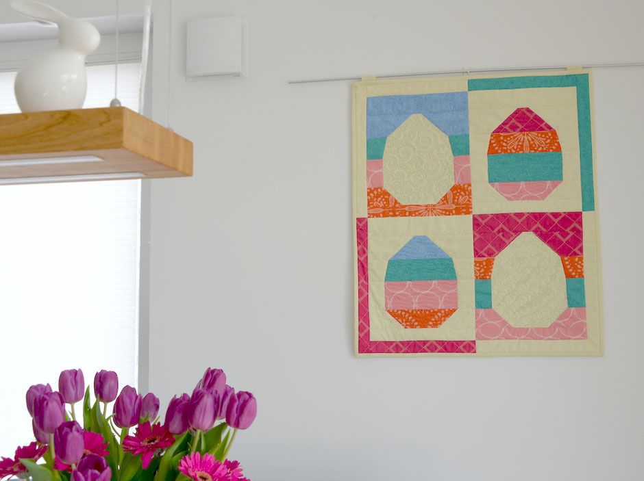 Osterei Quilt an der Wand, lila Tulpen im Vordergrund