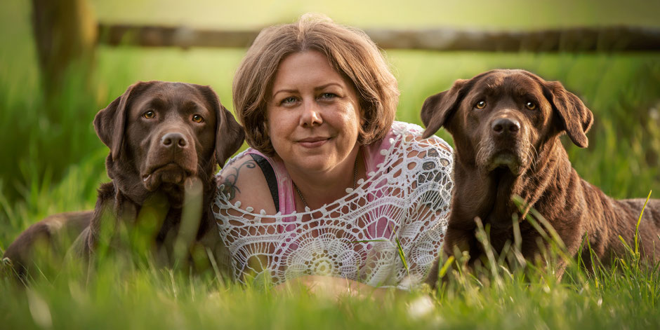 Rebecca Handwerk mit ihren beiden Hunden im Gras, ganzheitliche Seniorhundbegleitung
