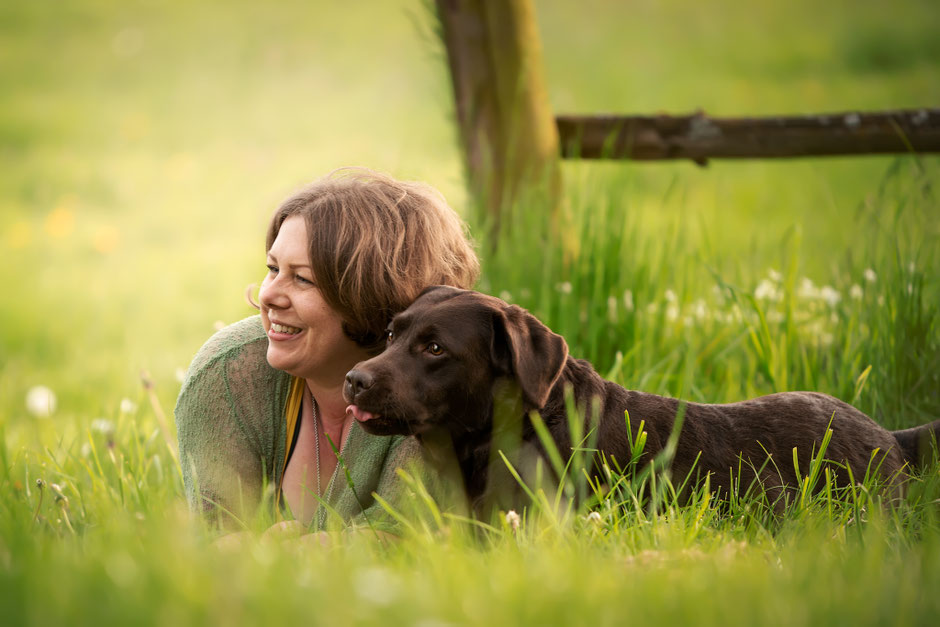 Rebecca Handwerk lacht im Gras mit ihrem Hund, tiefe Verbindung durch Tierkommunikation