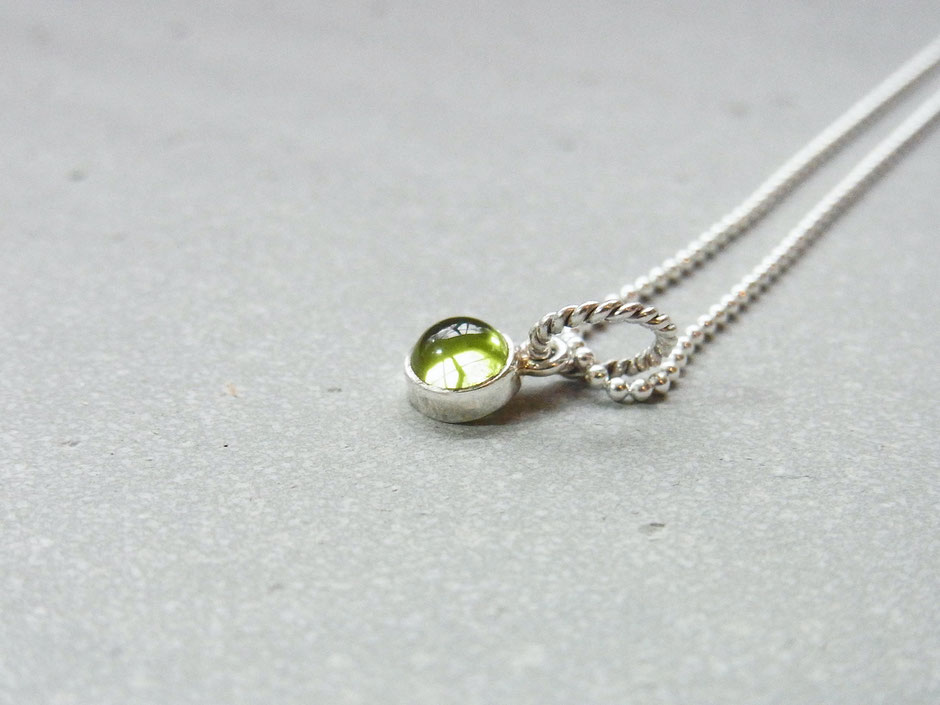 Kurze feine Kette mit einem kleinen runden hellgrünen Peridot Anhänger in Silber gefasst.