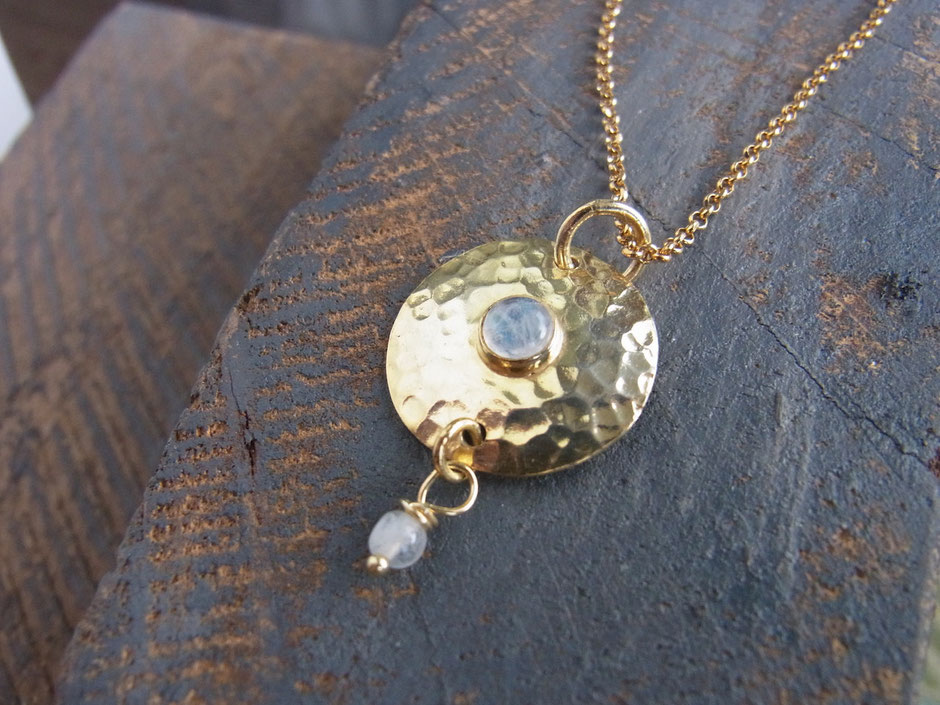 Filigrane Kette mit einem runden handgehämmerten Amulett mit Regenbogen Mondstein Amulett in gold, an dem eine kleine Mondstein-Perle hängt.