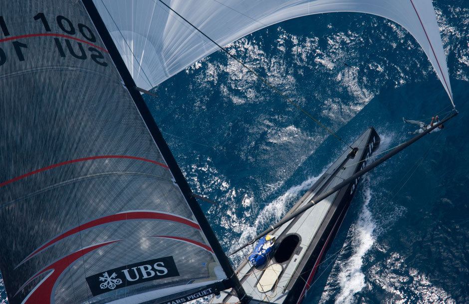 Top-View einer Segelyacht mit Spinnaker auf offenem Meer – Alinghi Boot als Symbol für Hochseeschein, Navigation, Offshore-Training.