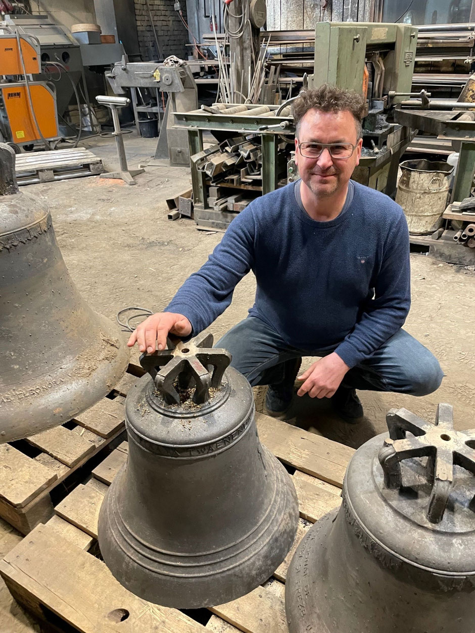 Rudolf Perner kniet vor der neu gegossenen Glocke.