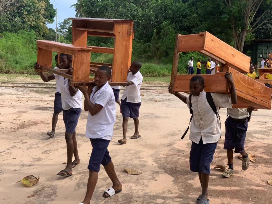 Afrikanische Schüler tragen ihre neuen Schulbänke.