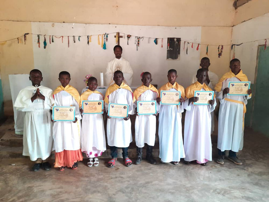 Afrikanische Kinder bei der Erstkommunion mit dem Pfarrer der Gemeinde.