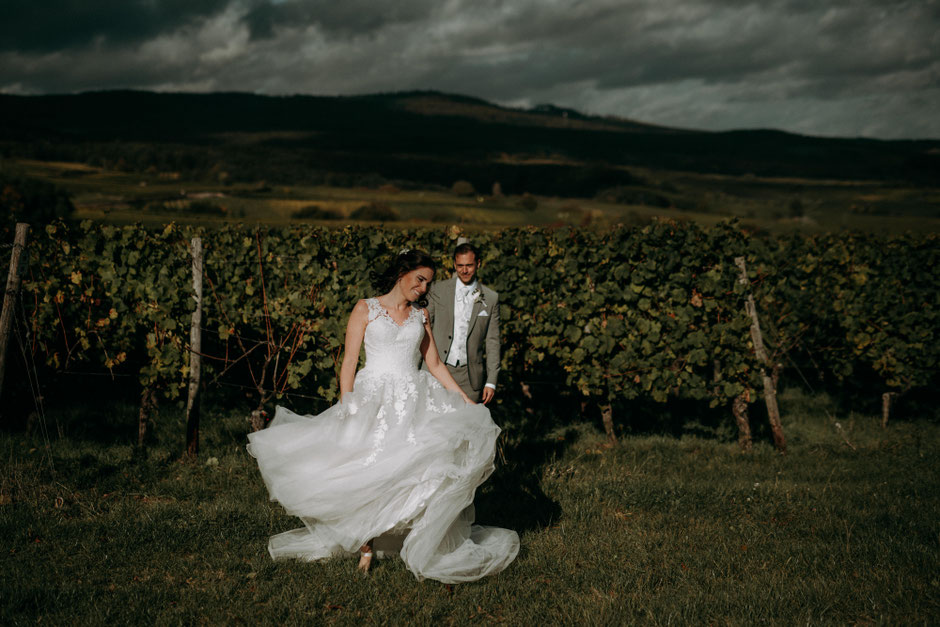 Braut tanzt im Weinberg im Rheingau und der Bräutigam sieht ihr dabei zu - Hochzeitsfotograf Rheingau
