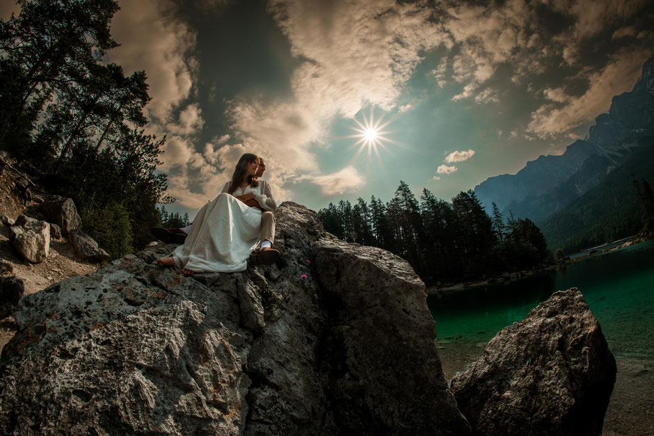 Hochzeitsfotograf Europa - Paar sitzt auf einem Felsen am Eibsee vor der Sasseninsel