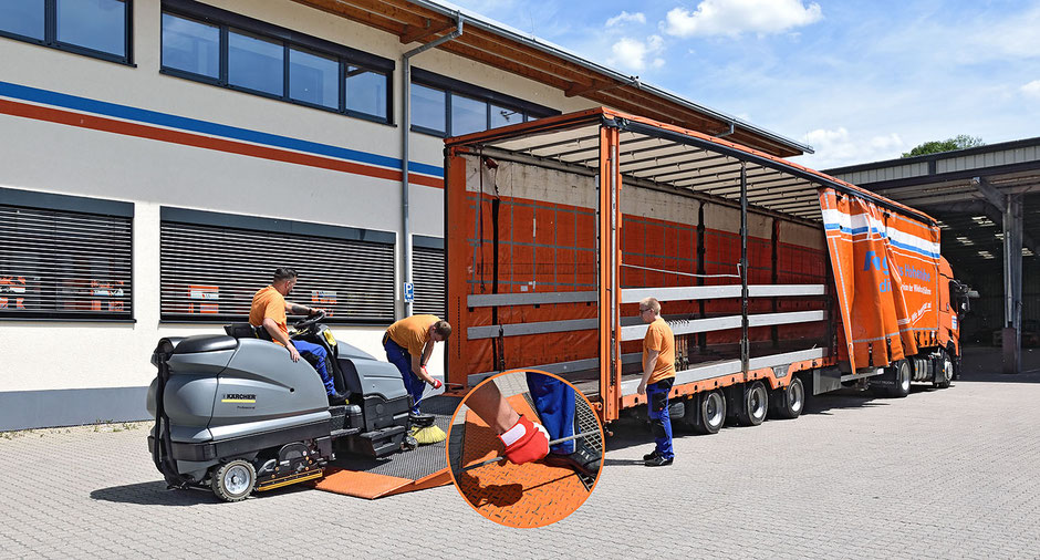 Drei Mitarbeiter in orangener/blauer Kleidung kümmern sich um die Beladung eines Planentiefladers mit einer Kehrmaschine. Eine Seitenwand des Lkw ist geöffnet. In der Mitte ist ein orangener Kreis mit der Vergößerung eines Details (Seilwinde).