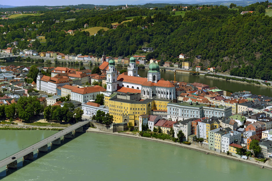 Die bunten Häuser der Passauer Altstadt umrahmen den imposanten Dom. Gemeinsam liegen sie auf einer Landzunge rechts und links davon die Flüsse Donau und Inn.