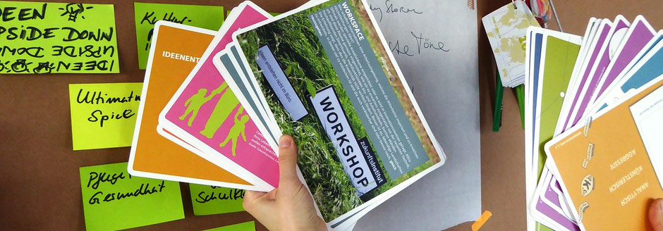 Eine Hand pinnt Kärtchen für einen Workshop an die Pinnwand