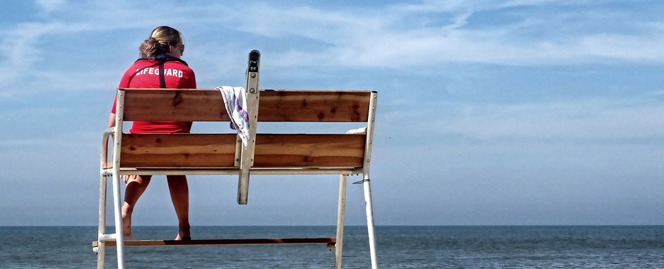 Eine Rettungsschwimmerin sitzt auf einem Hochsitz und schaut aufs Meer