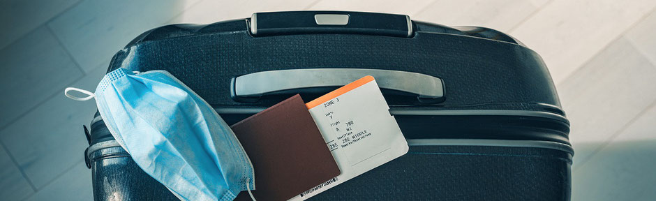Corona-Urlaub: Koffer mit Maske, Pass und Flugticker für den Urlaub. Nun in Quarantäne zu Hause. Was leistet die ERGO Reiseversicherung im Schadensfall?