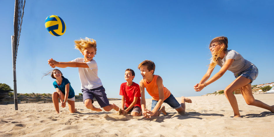 Fröhliche Kinder am Strand während ihrer Freizeitreise