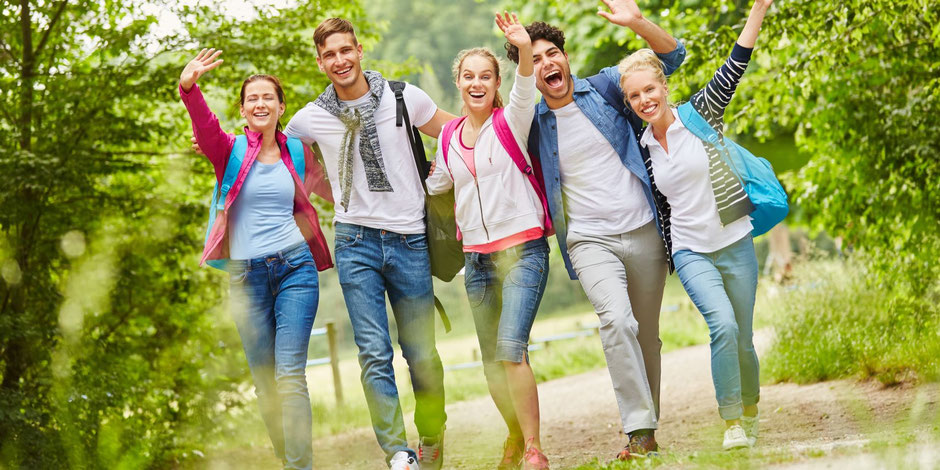 Fröhliche Schülergruppe auf Klassenfahrt – sicher unterwegs mit dem Kinder-, Schüler & Jugendreiseschutz.