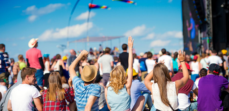 Während eines open-Air Konzerts: Gruppe von Jugendlichen sitzt auf einer Wiese - gut abgesichert mit der ERGO Eintrittskarten-Versicherung für Tickets