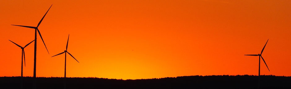 Geld sparen in der Corona-Krise: Silhouette von Windrädern in der Morgensonne