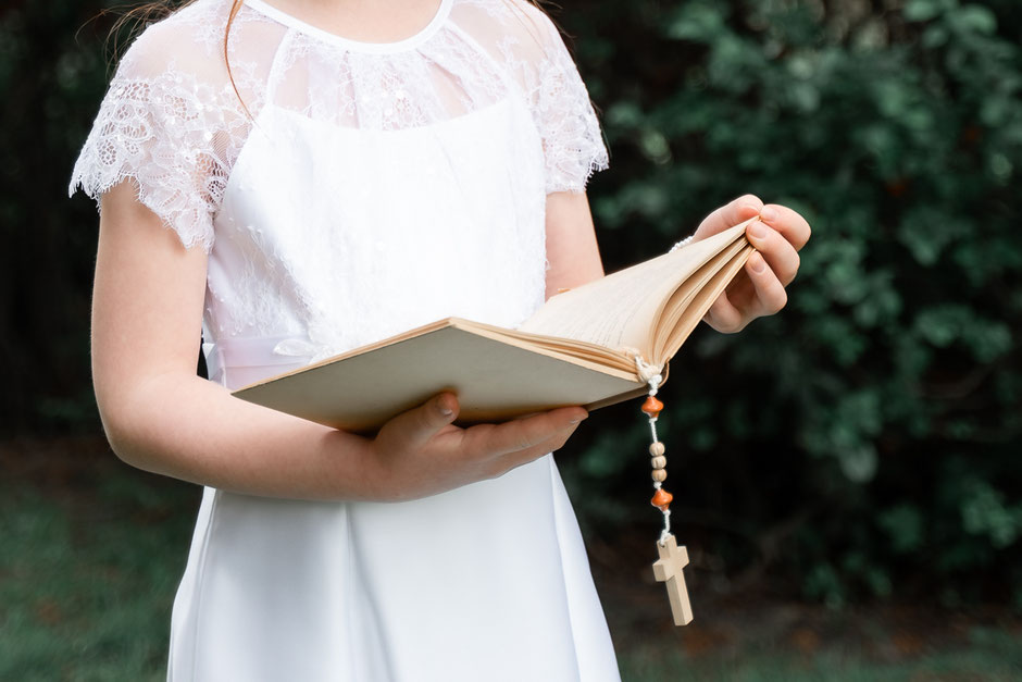 Ein Mädchen in festlichem weißen Kleid feiert ihre Heilige Erstkommunion. Andächtig in der Kirche und strahlend vor der Kirche – ein besonderer Moment voller Glaube und Freude.