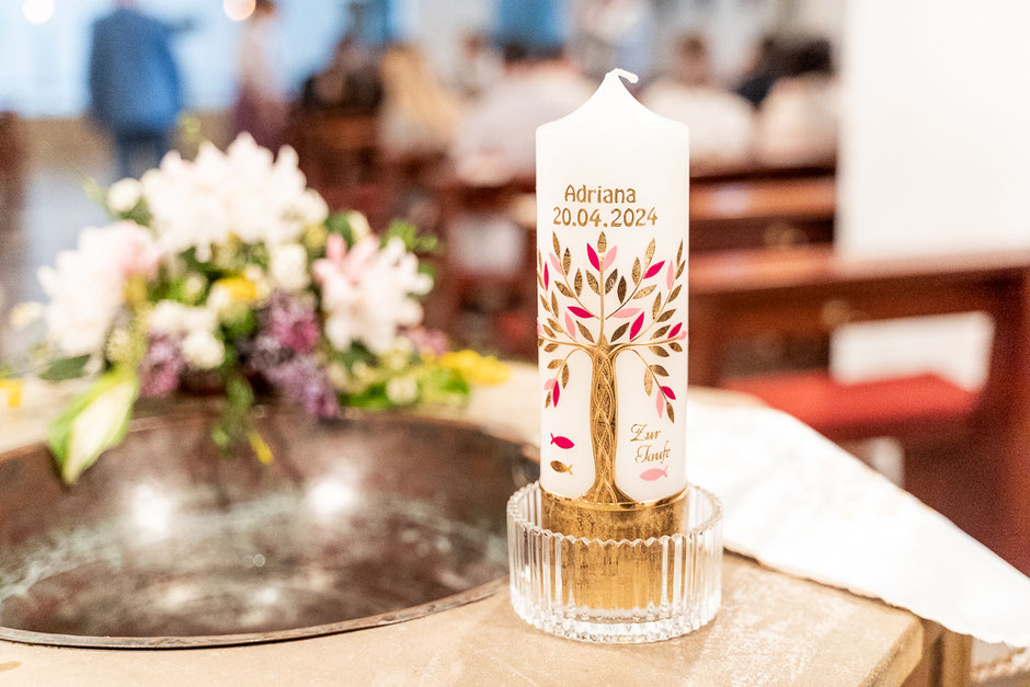 Ein kleines Mädchen beobachtet andächtig, wie ihre Taufkerze in der Kirche entzündet wird. Ein feierlicher Moment voller Symbolik und Licht im Rahmen der Tauffeier.