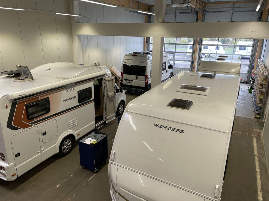 Blick in die geräumige Werkstatt von Beständig Campers mit mehreren Wohnmobilen und Wohnwagen der Marke Weinsberg, die zur Wartung und Instandsetzung in den Servicebuchten stehen