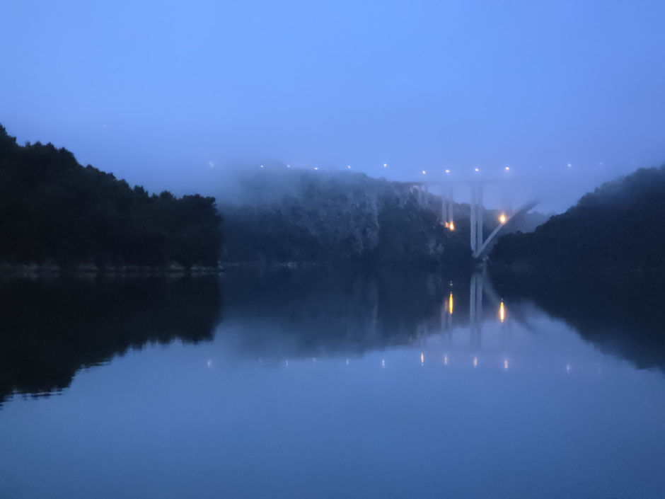 Nebelverhangene Brücke über stillem Wasser im Morgengrauen – Symbol für Übergang, Klärung und geistige Navigation.