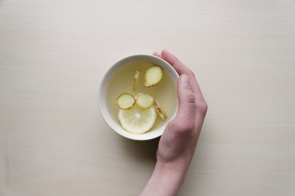 hand with a cup of ginger lemon tea