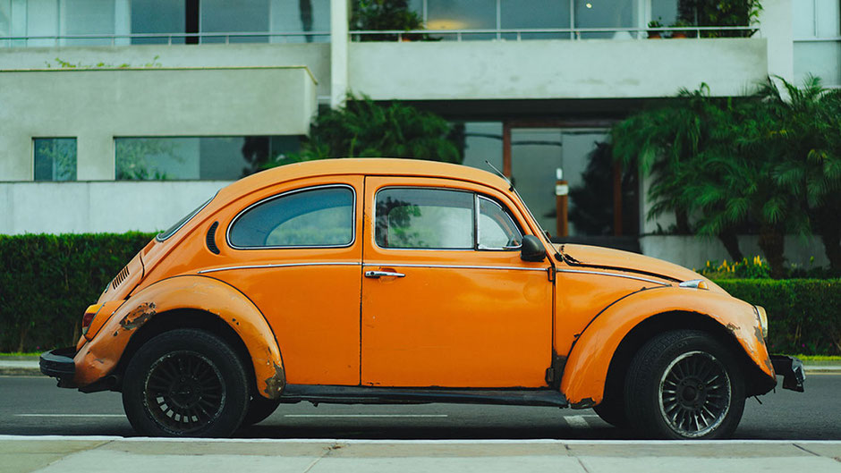 Ein alter VW-Käfer in der Farbe Orange mit Rost am Straßenrand. Für ein neues Auto erstellt ihnen die unabhängige Finanzberaterin Melanie Schneider von Eloquent Invest Ihr individuelles Konzept für einen Privatkredit.