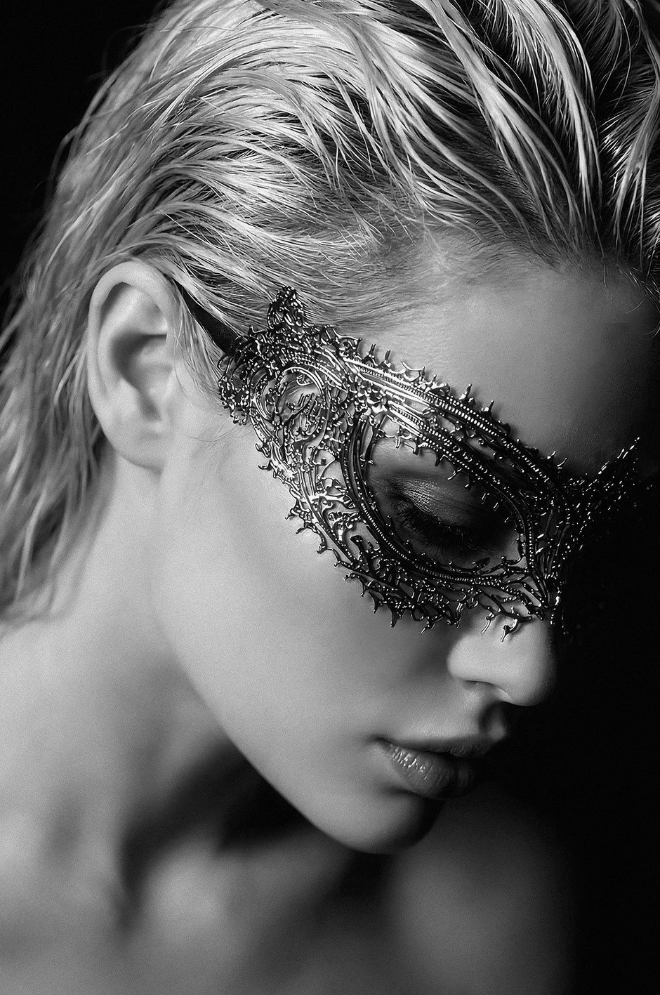 Fine art BW portrait of a beautiful woman with a Venetian mask and short blonde hair
