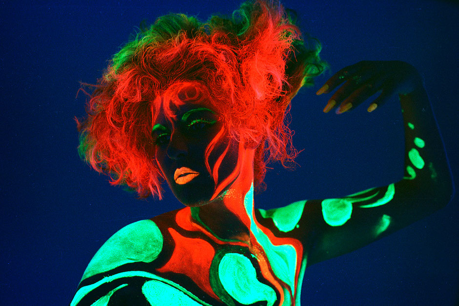 A nude woman with fluorescent make up styling, red hair combined with green and black